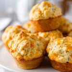 Golden-brown Cheddar Dill Muffins arranged on a white plate, highlighting their crispy tops and fresh dill sprinkles.