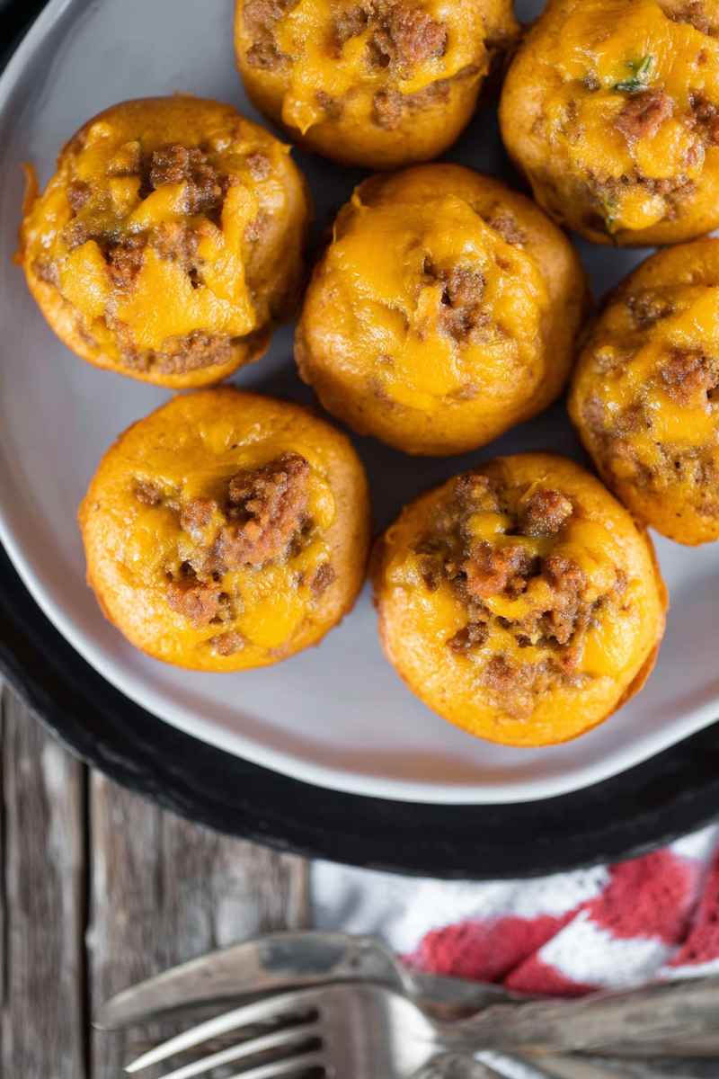 A plate of golden cheeseburger muffins filled with ground beef and topped with melted cheddar cheese.