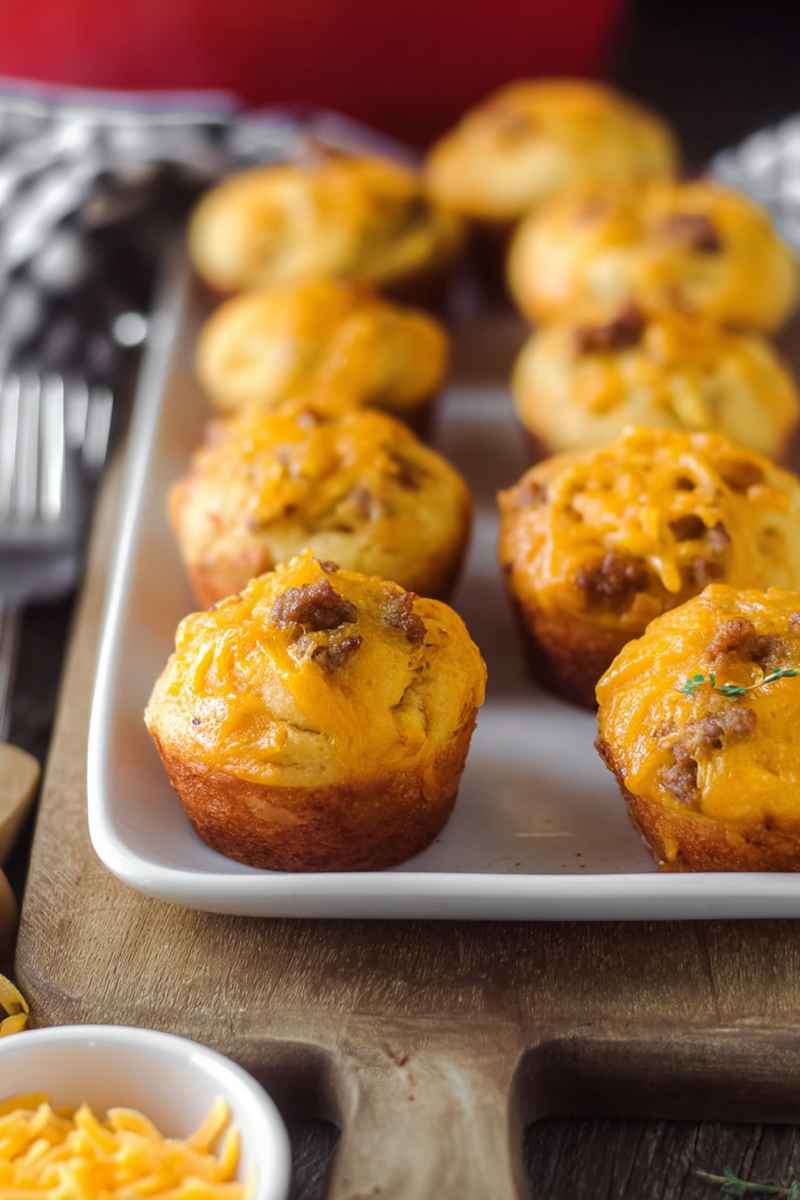 A tray of golden cheeseburger muffins with melted cheese and ground beef toppings, ready to serve.