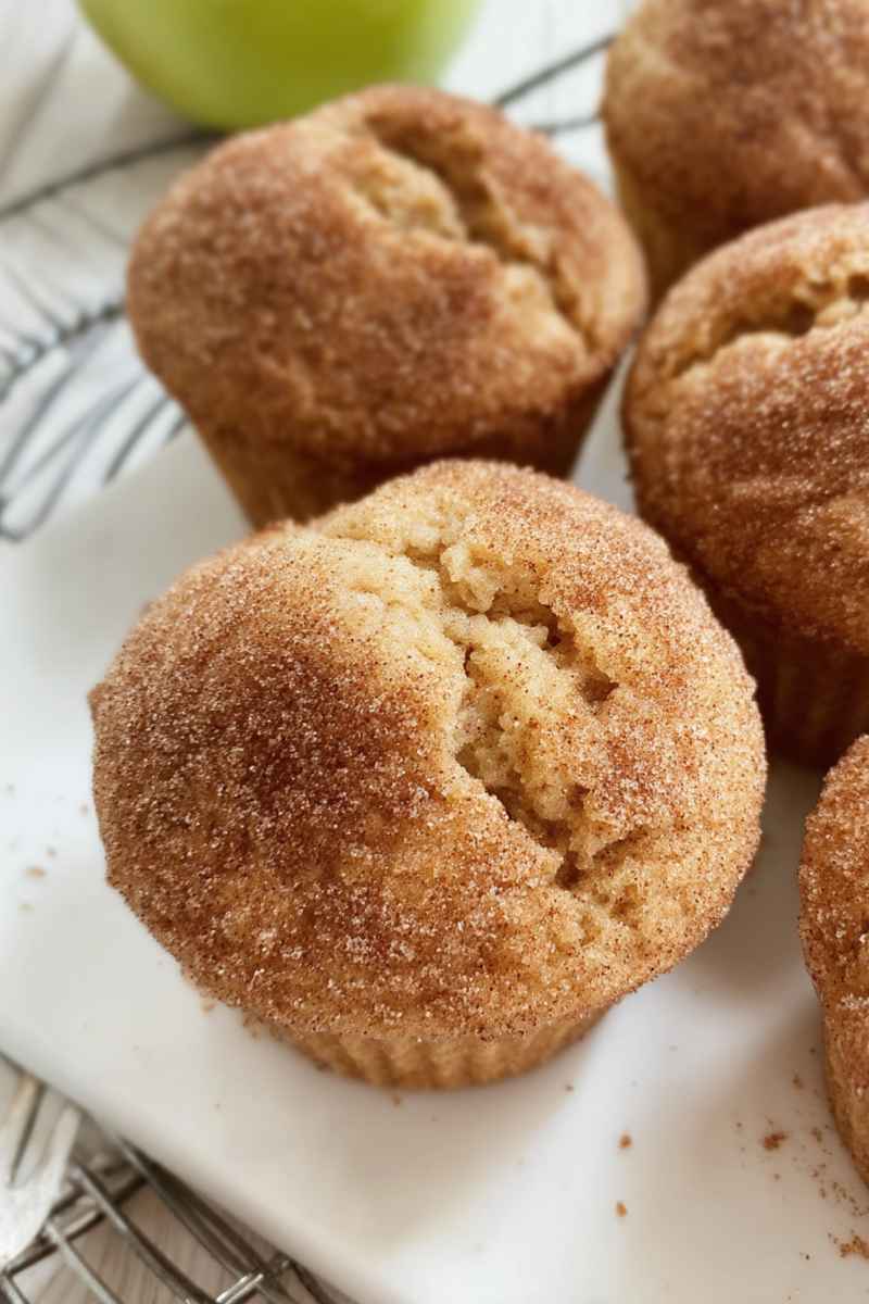 A close-up of a halved cinnamon applesauce muffin, highlighting its tender crumb and golden-brown cinnamon sugar coating.