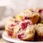 A stack of freshly baked coconut lemon raspberry muffins, highlighting their golden exterior and juicy berry filling.