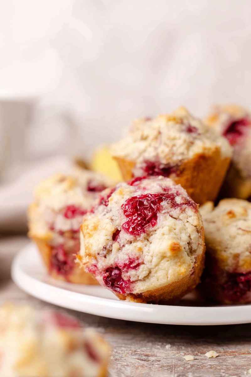 A stack of freshly baked coconut lemon raspberry muffins, highlighting their golden exterior and juicy berry filling.