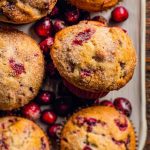 Delicious Cranberry Muffins arranged on a white tray, garnished with fresh cranberries.