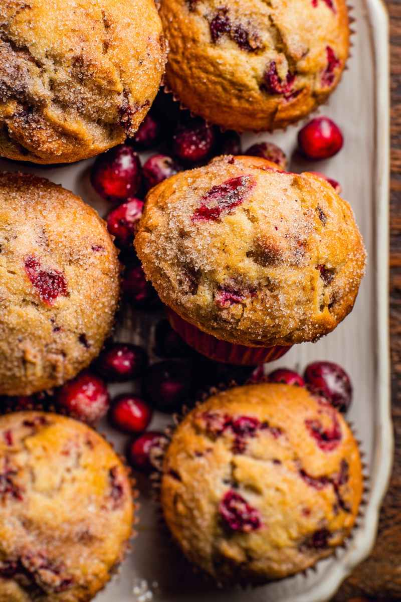 Delicious Cranberry Muffins arranged on a white tray, garnished with fresh cranberries.