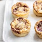 Creamy Jammy Coffee Cakes with layers of cake, cream cheese, jam, and streusel topping on a white tray.