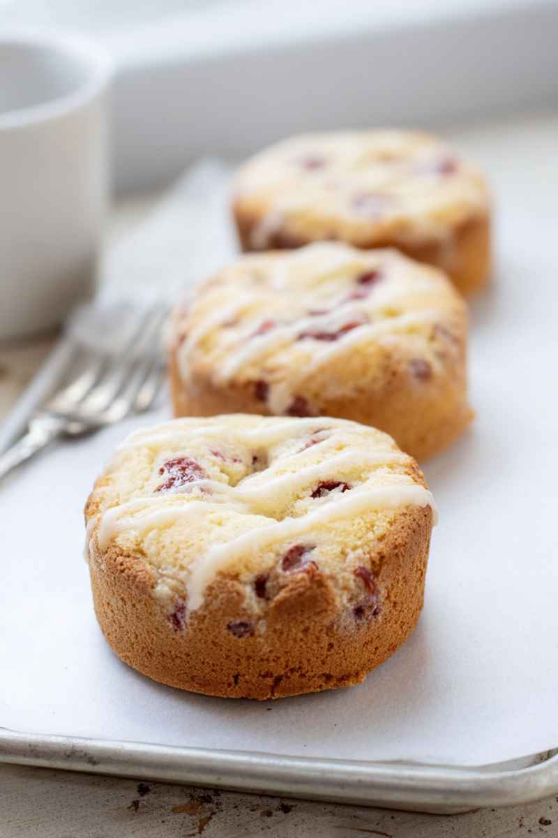 Mini cakes topped with a glossy raspberry glaze on a white plate.