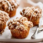 Golden Crumb Cake Muffins with a thick layer of cinnamon-sugar crumbs and a glossy icing drizzle.