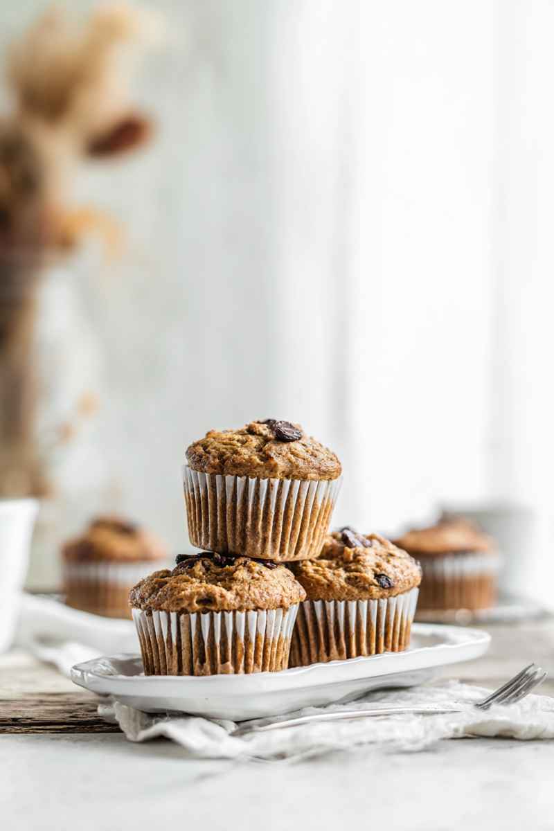 Golden Peanut Butter Banana Muffins with dark chocolate chips, arranged on a white plate.