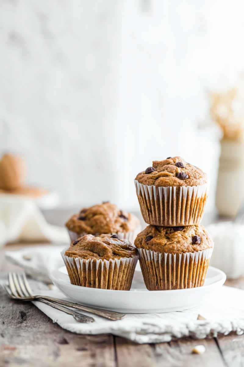Golden Peanut Butter Banana Muffins with dark chocolate chips, presented on a white plate.