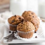 Golden Peanut Butter Banana Muffins with dark chocolate chips, served on a white plate.