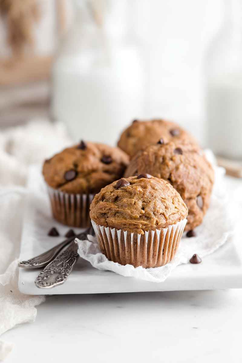 Golden Peanut Butter Banana Muffins with dark chocolate chips, served on a white plate.