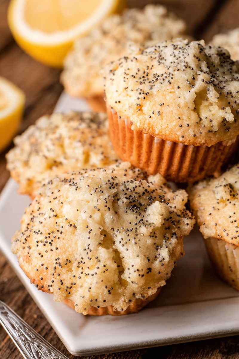 Golden Lemon Poppy Seed Muffins with visible black poppy seeds, arranged on a white plate.
