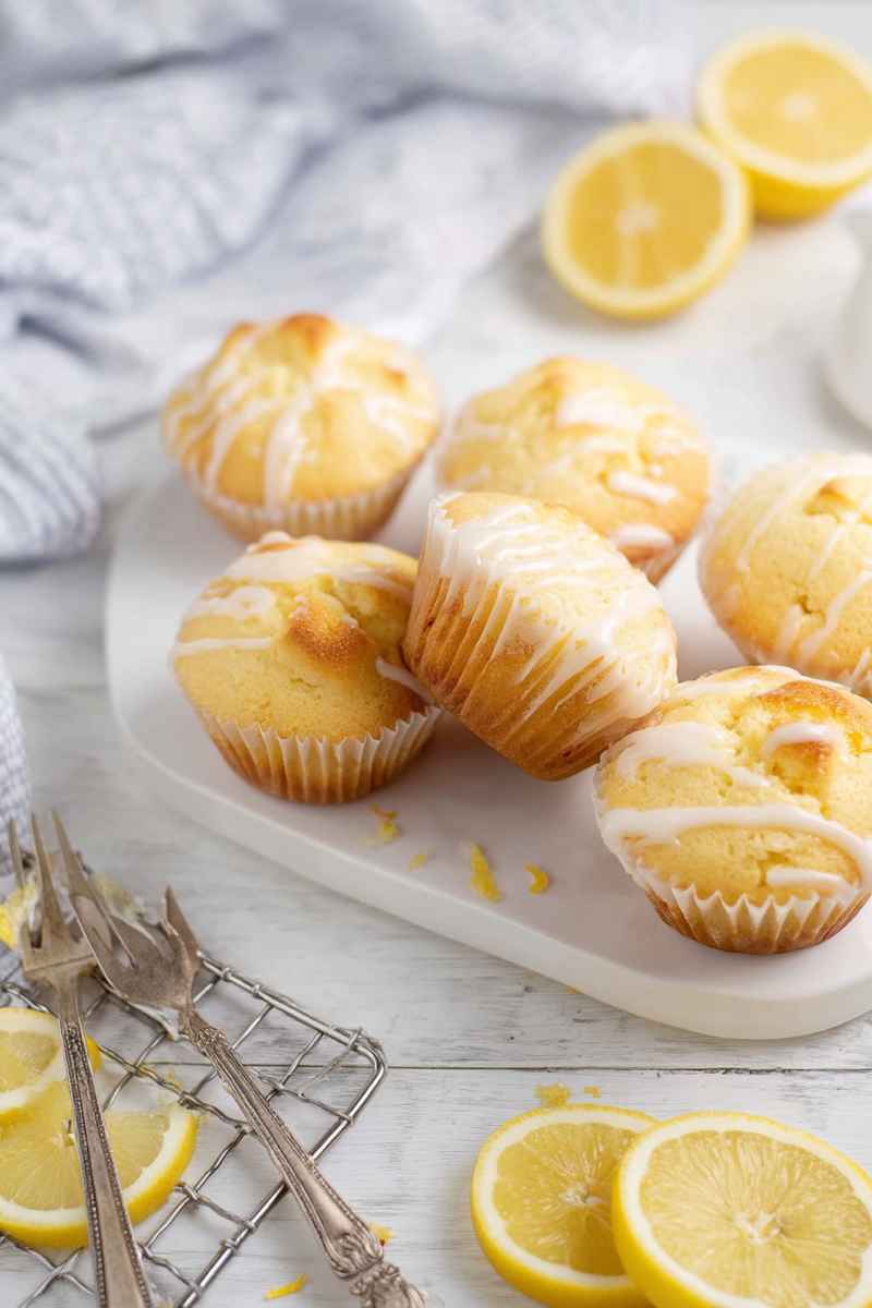 A plate of Lemon Pound Cake Muffins surrounded by slices of fresh lemons, ready to be enjoyed.
