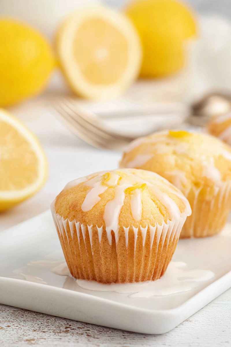 A close-up of a Lemon Pound Cake Muffin with a glossy lemon glaze, placed on a white plate.