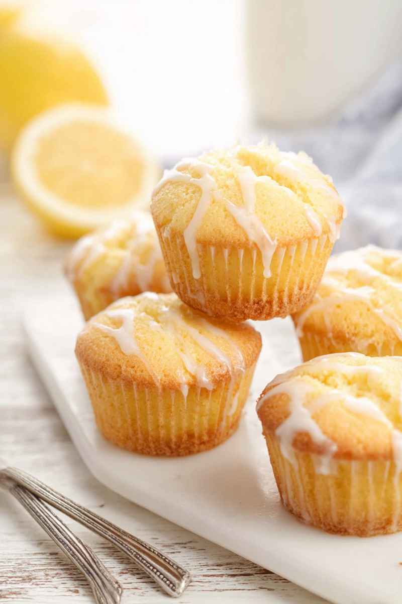 Golden Lemon Pound Cake Muffins drizzled with a creamy white glaze, served on a white plate.