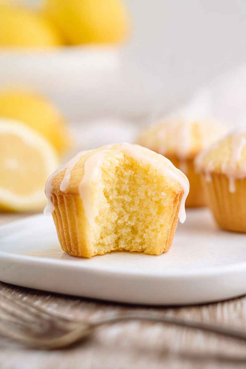 A partially eaten Lemon Pound Cake Muffin showcasing its soft, moist interior, drizzled with lemon glaze.