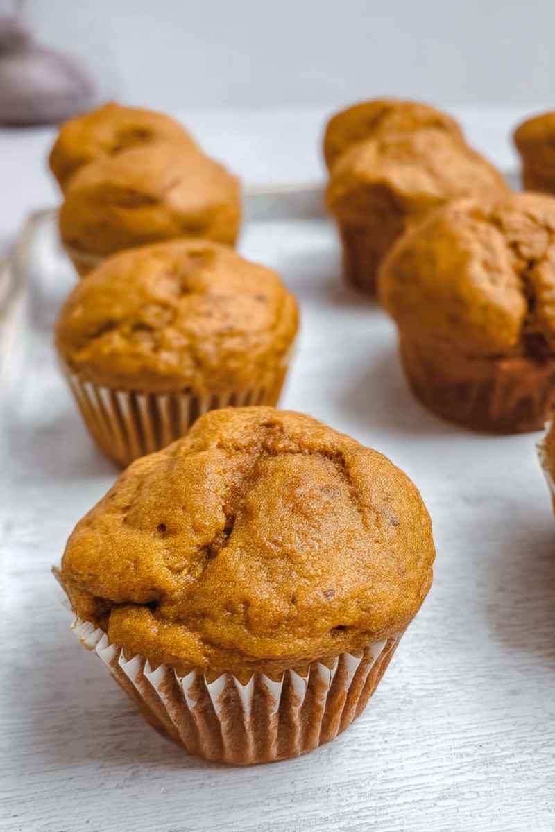 Close-up of golden pumpkin protein muffins with a soft, slightly cracked top, ready to be enjoyed.