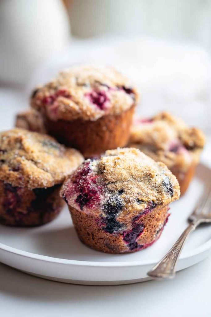A plate of mixed berry muffins, showcasing their golden-brown tops and colorful berry fillings, ready to be enjoyed.