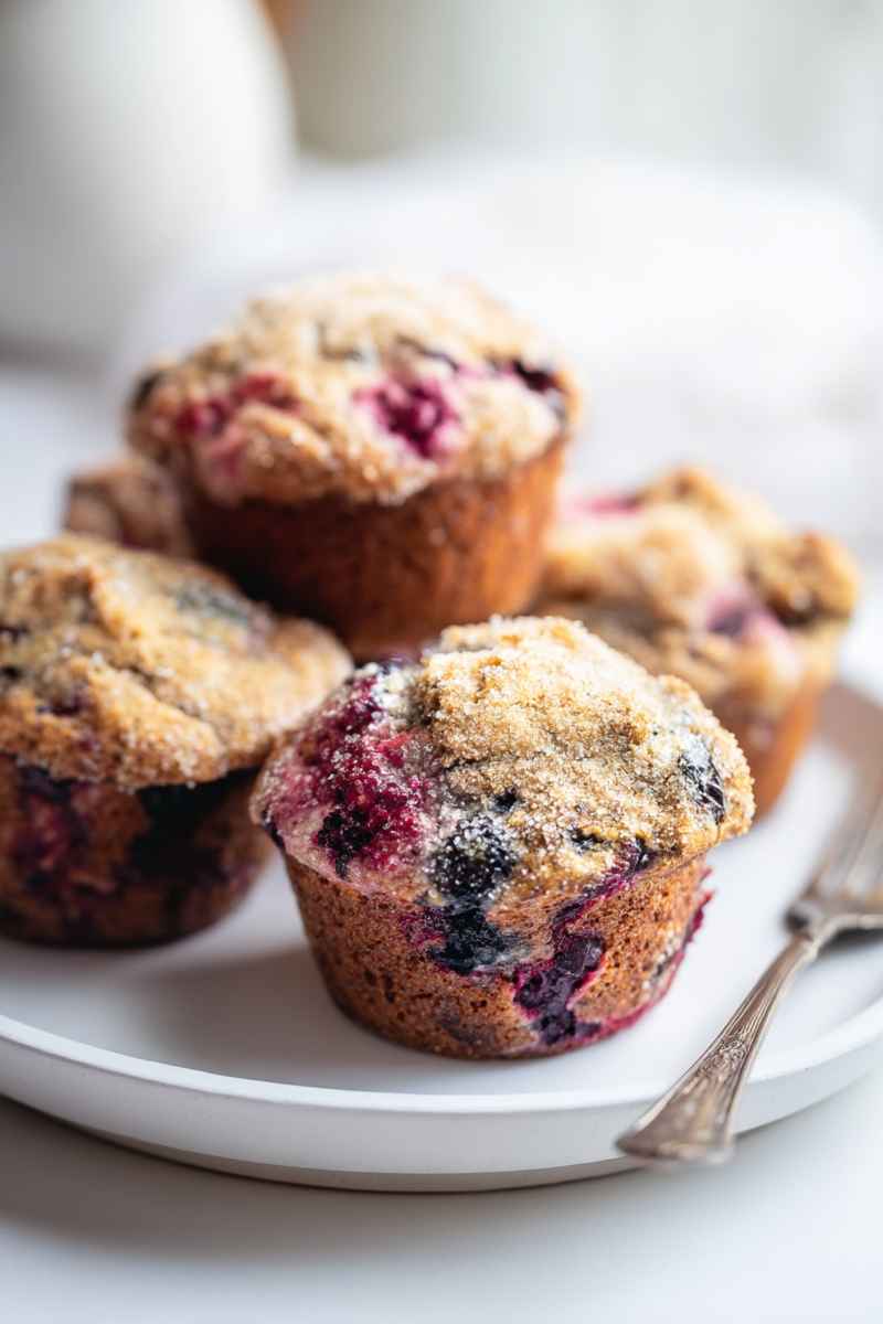 A plate of mixed berry muffins, showcasing their golden-brown tops and colorful berry fillings, ready to be enjoyed.