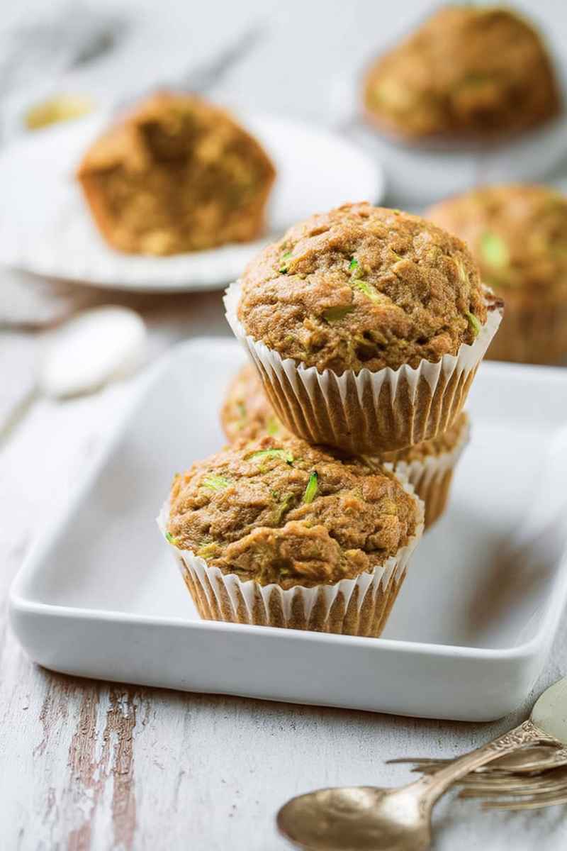 Two zucchini muffins stacked on a white tray, highlighting their golden-brown crust.