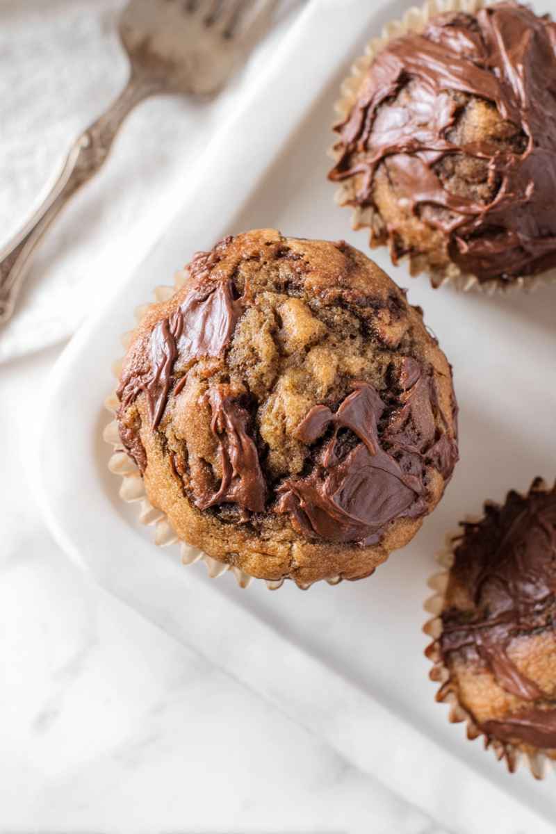 Golden brown banana muffins with a decadent Nutella swirl topping.