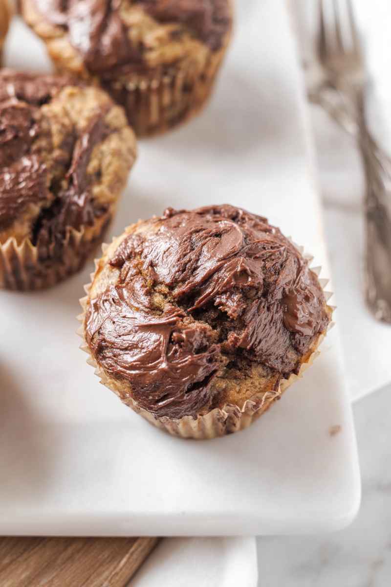 Fluffy banana muffins with a rich Nutella swirl, ready to eat.