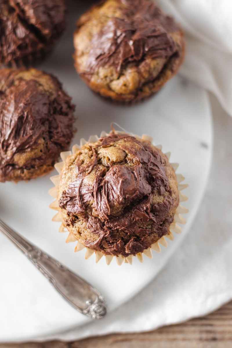 Golden brown banana muffins topped with a luscious Nutella swirl, ready to be savored.