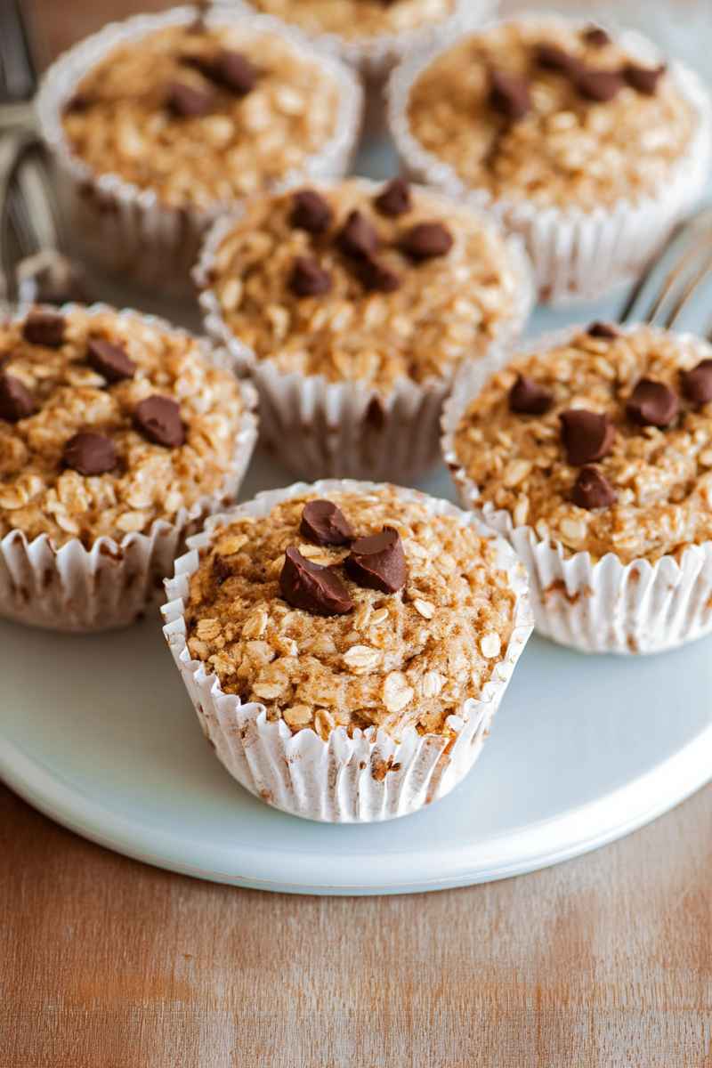 Golden oatmeal muffins with scattered chocolate chips, presented on a light blue plate.