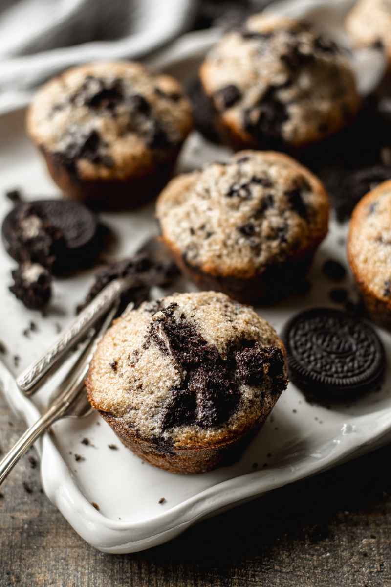 Close-up of Oreo muffins on a white plate, showcasing their tender texture and Oreo-studded tops.