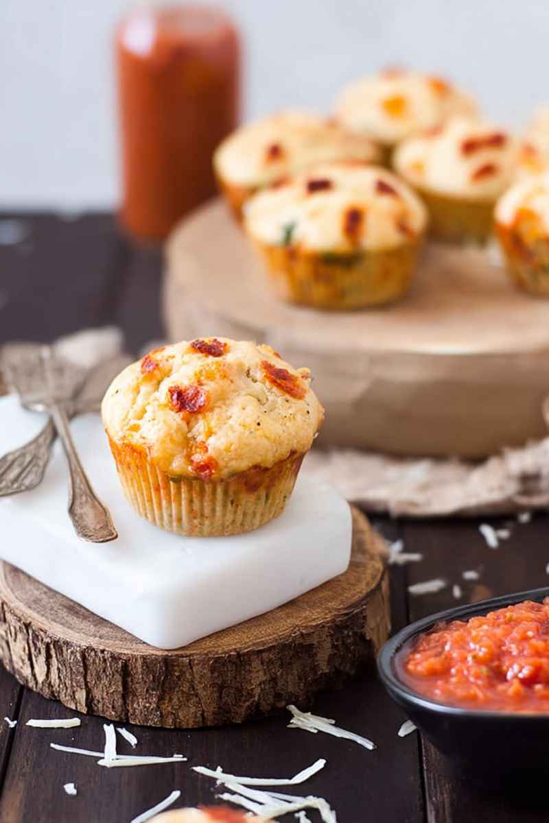 Golden pizza muffins with melted cheese and tomato toppings, displayed on a rustic wooden board.