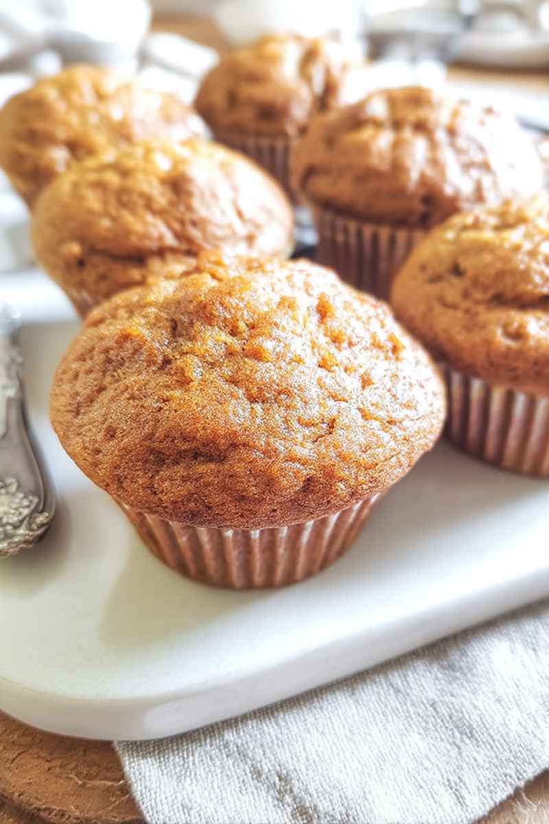 A plate of golden-brown Sour Cream Applesauce Muffins, showcasing their bakery-style charm and inviting texture.