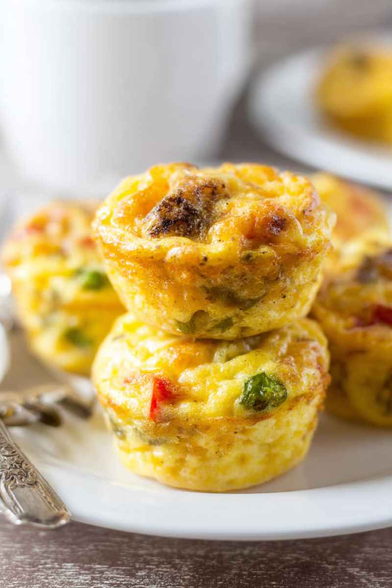A close-up of golden egg muffins filled with colorful vegetables and sausage, showcasing their appetizing texture.